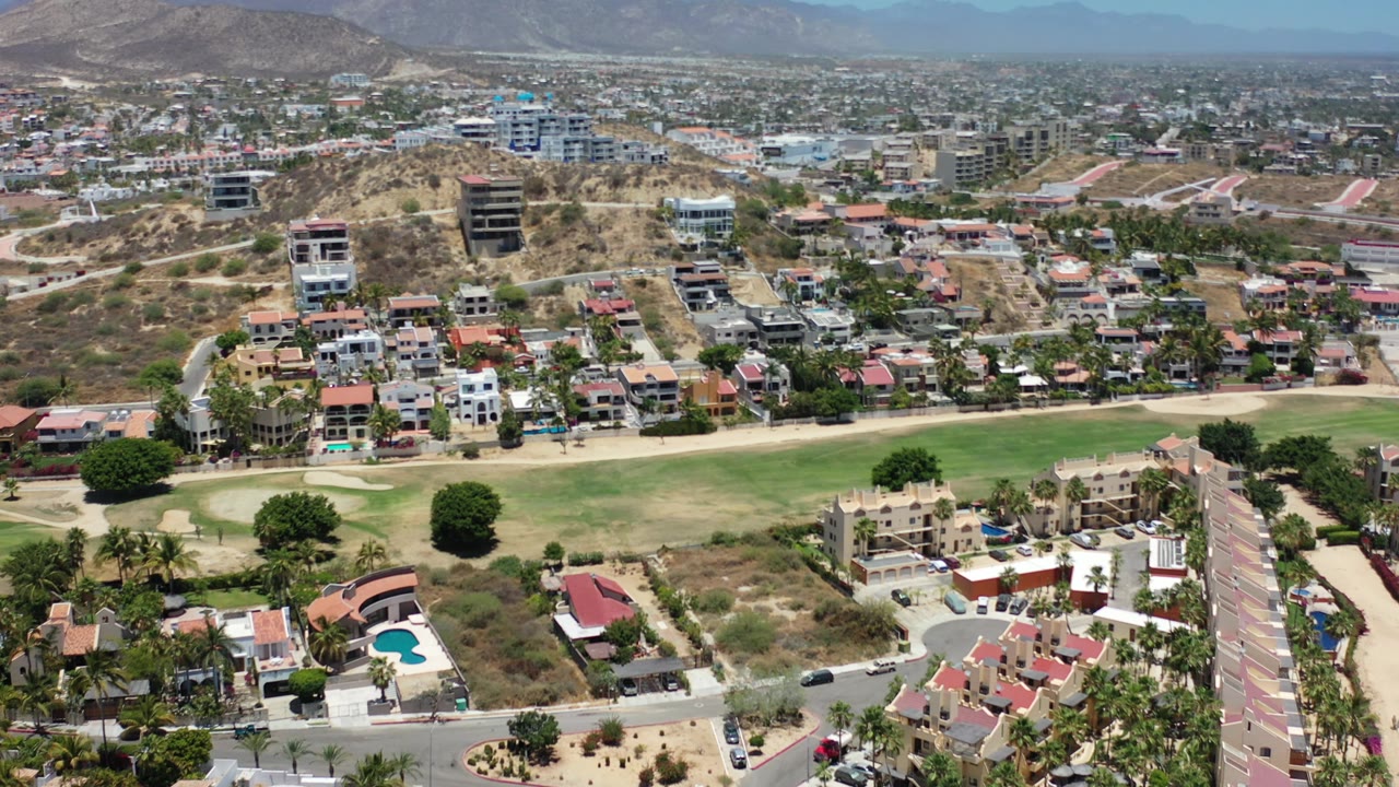 Aerial neighborhood view with fairway, homes, and hills.