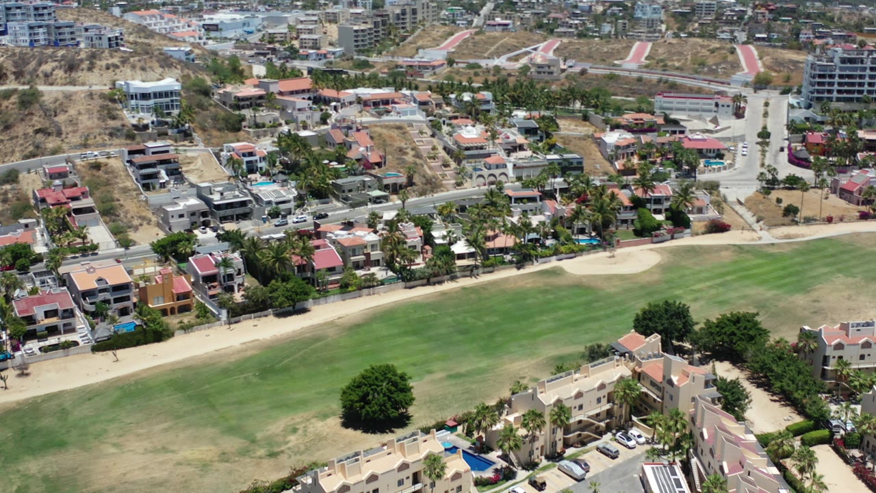 Aerial view of green landscaped grounds beside residential streets and houses.