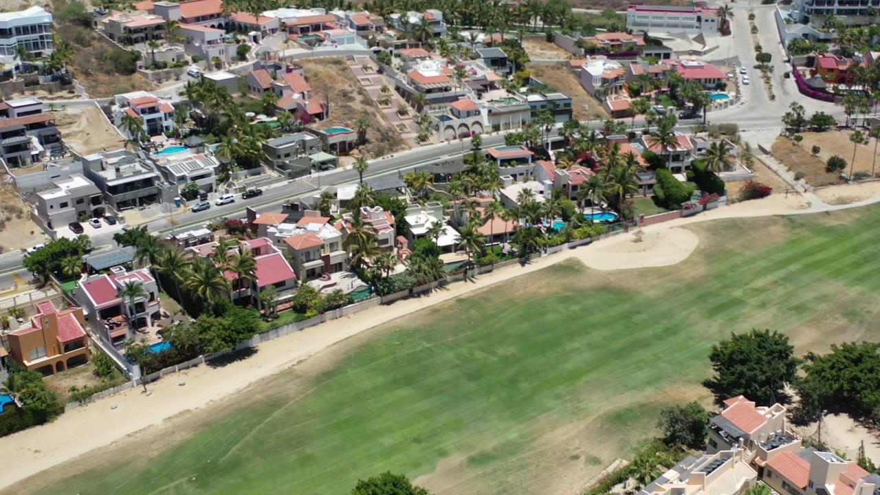 Aerial view of homes beside a large green lawn and road.