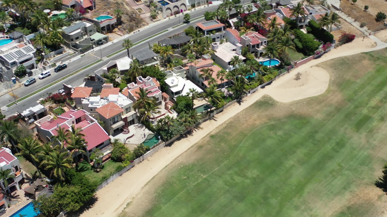Aerial view of houses beside a green fairway and road.