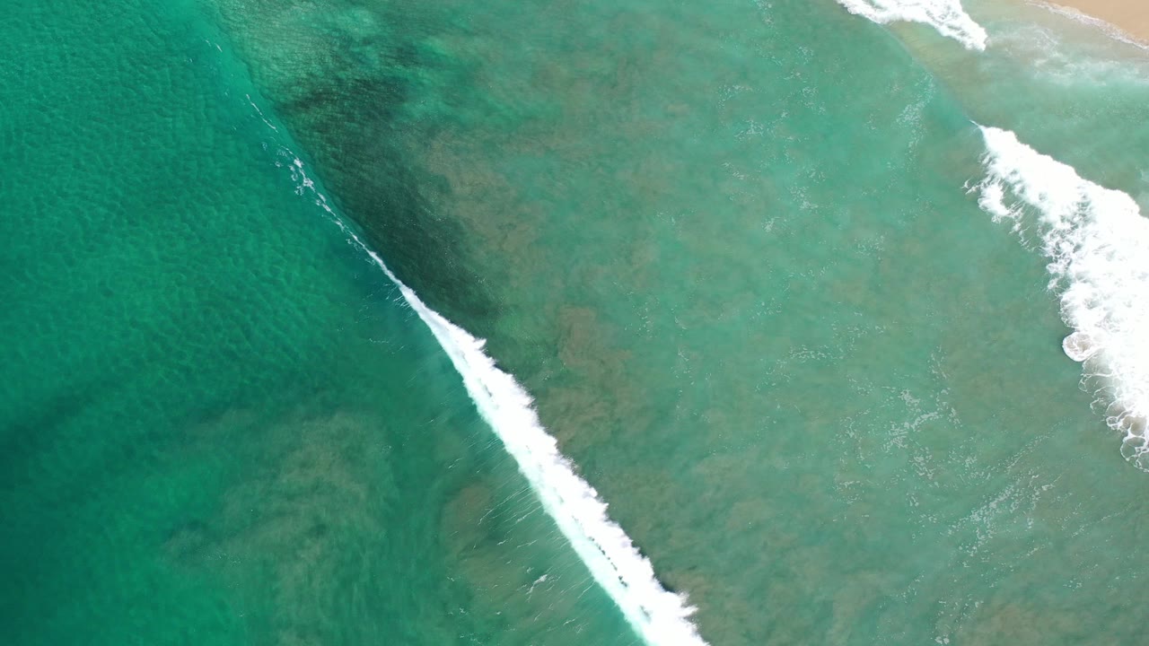Overhead turquoise water with a diagonal white wave near shore.