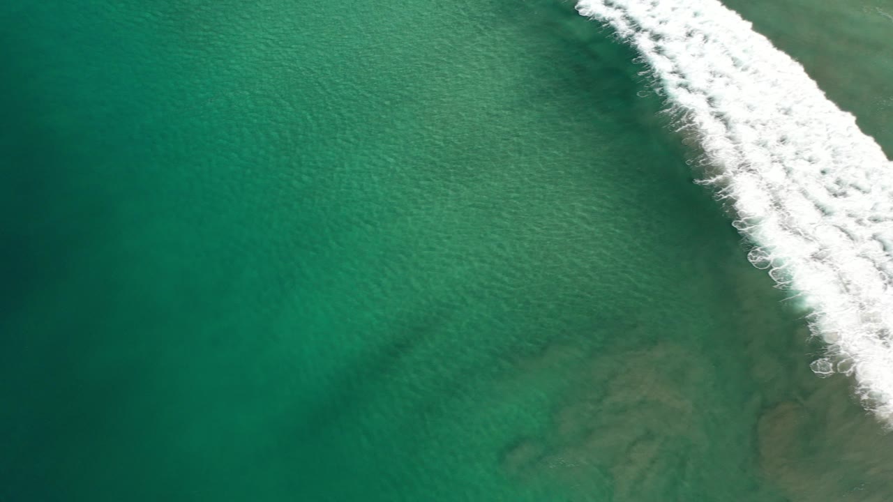 Overhead turquoise ocean with white surf at the upper right.