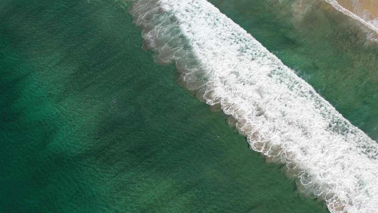 Breaking surf near shallow sandy water.
