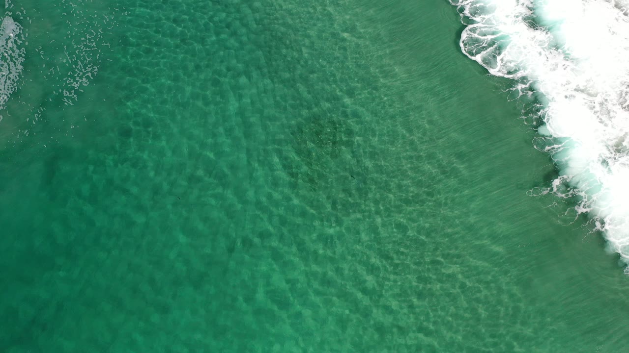 Overhead ocean surface with bright surf entering from the upper right.