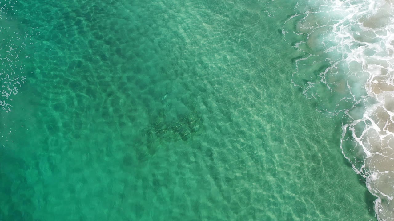 Transparent sea surface with ripples and surf on the right