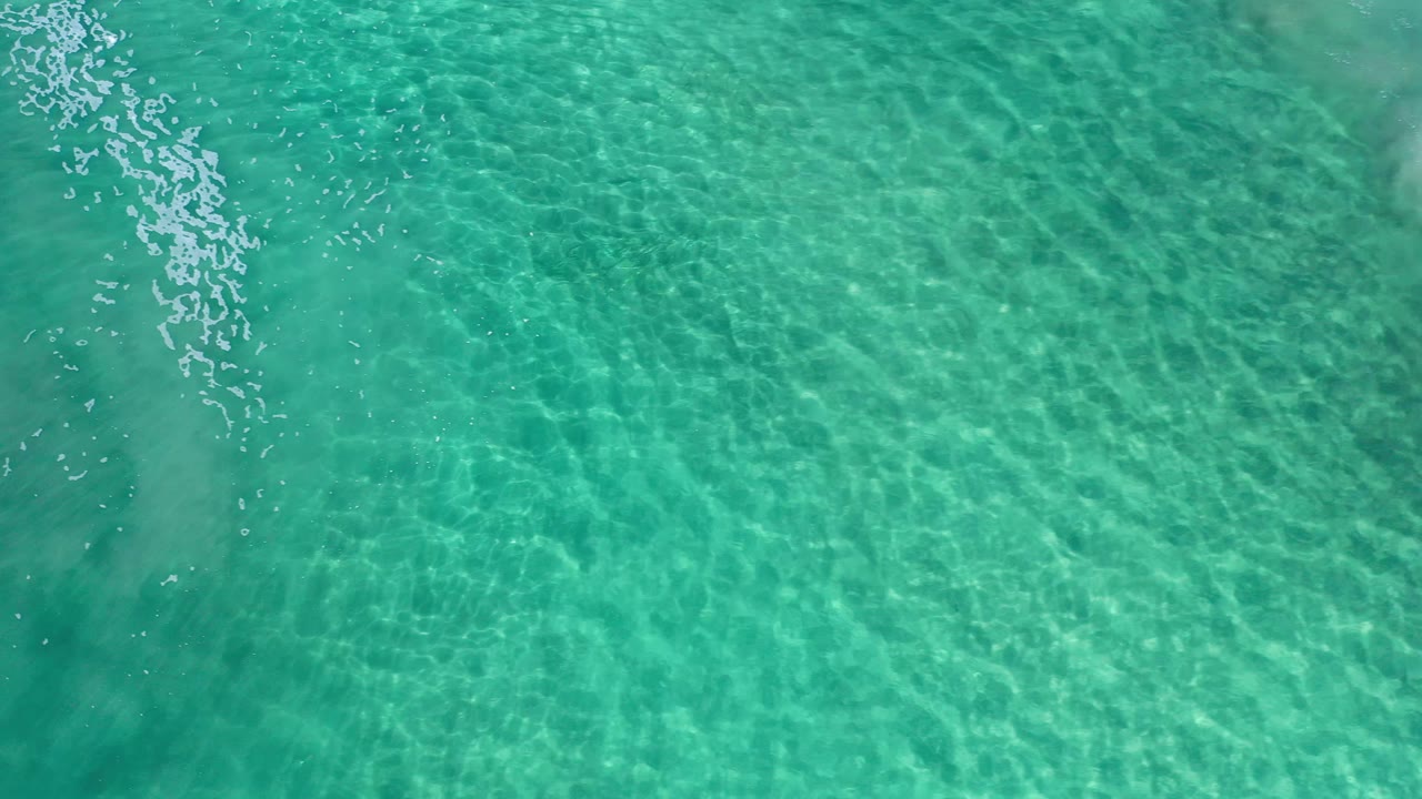 Clear blue-green sea water in Los Cabos, Mexico, fills the frame with bright caustic ripple patterns and no visible people.