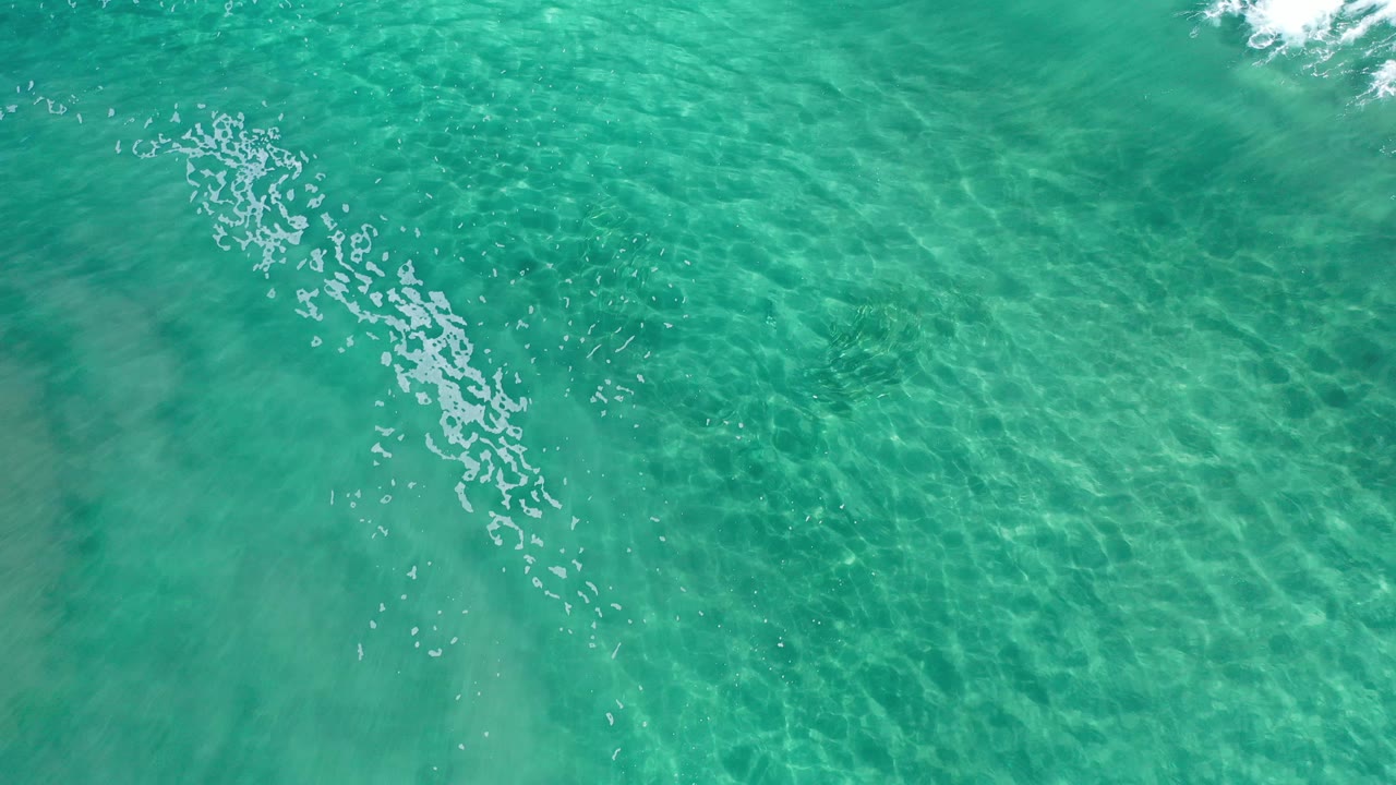 Turquoise shallow water with foam near the top edge.