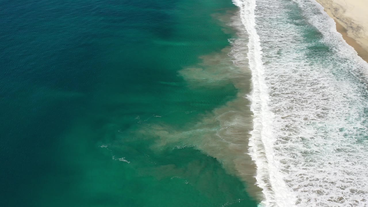 Aerial coastline with green-blue water and breaking surf
