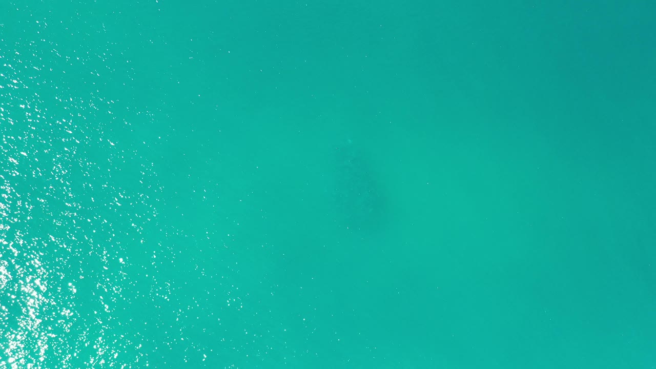 Turquoise ocean surface with sun reflections near the right side