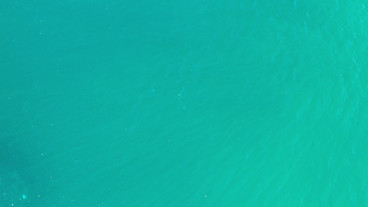 Top-down view of turquoise green sea water in Los Cabos, Mexico, with faint ripples and no visible people.