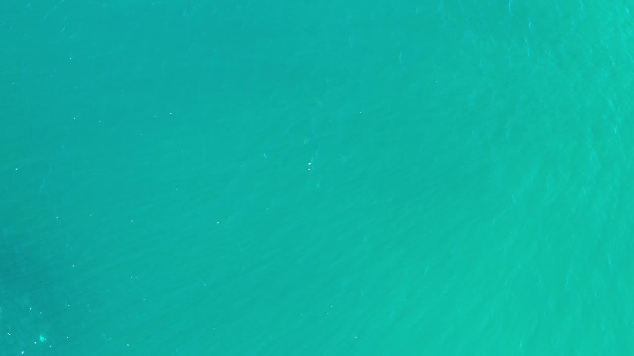 Overhead Los Cabos sea surface with soft green-blue color shifts, light ripple marks, and no visible people.