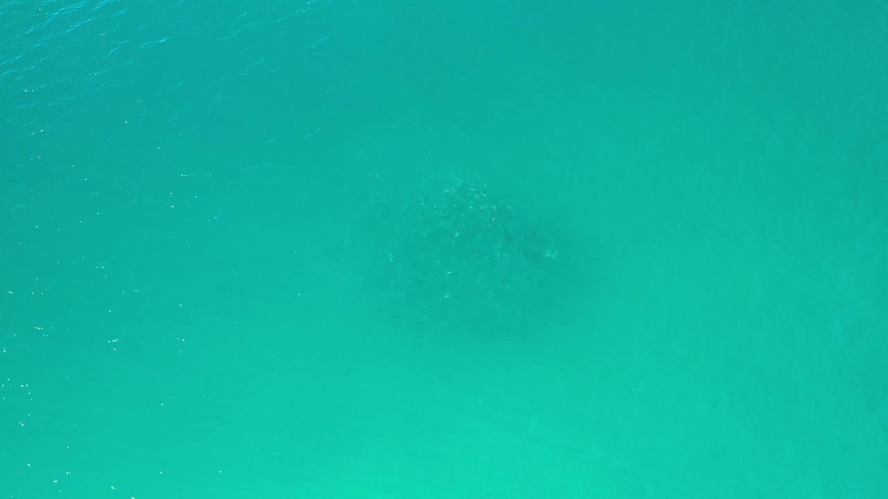 Aqua ocean surface in Los Cabos, Mexico, with a soft darker area near the left side and no visible people.