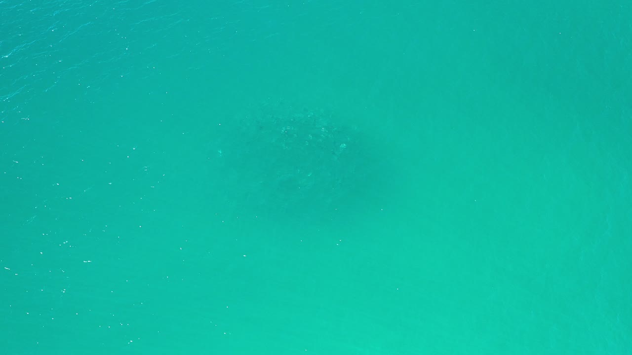 Overhead view of turquoise green ocean water in Los Cabos, Mexico, with faint darker patches under the surface and no visible people.