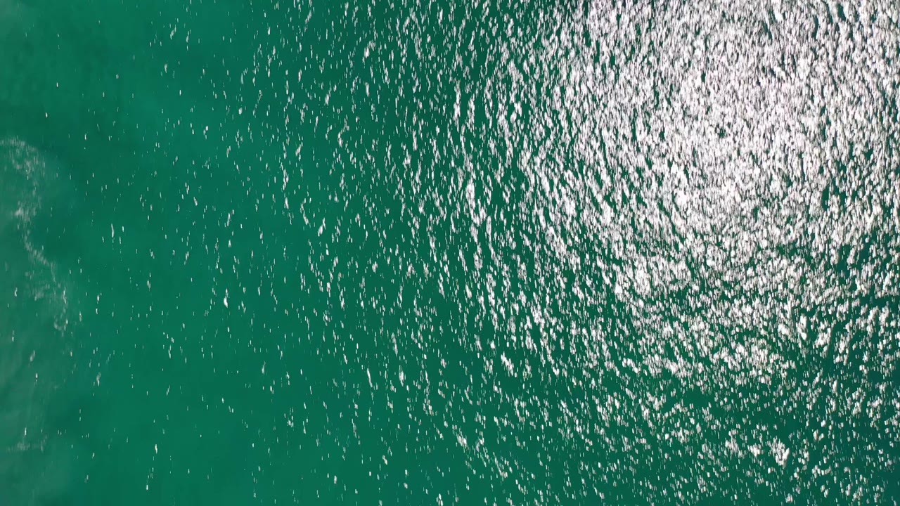 Green-blue ocean water with sun glare toward the upper right.