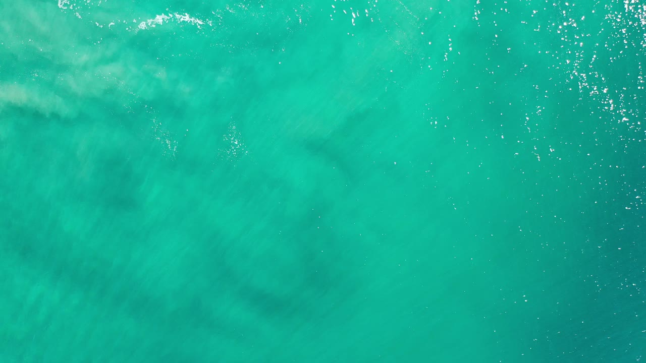 Bright teal water with soft white wave marks under the surface.