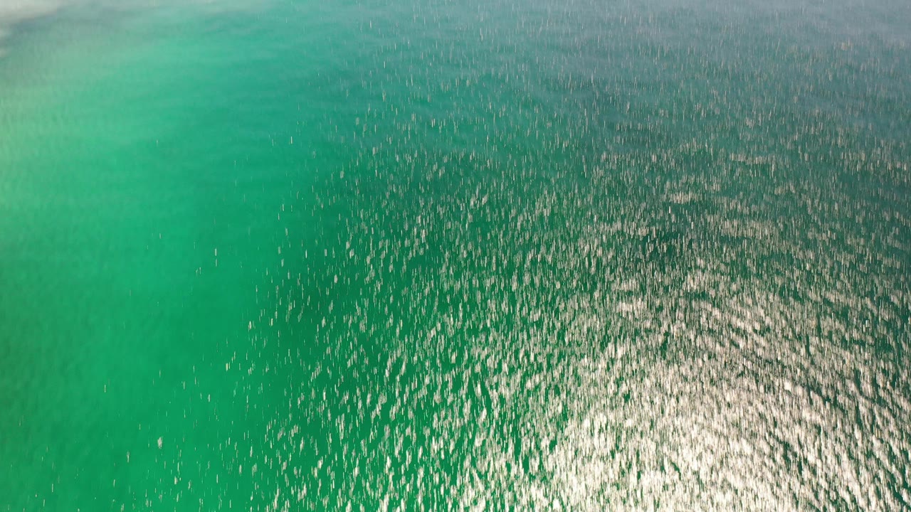 Overhead view of turquoise sea in Los Cabos, Mexico, with dense sunlight sparkle across rippled water and no visible people.