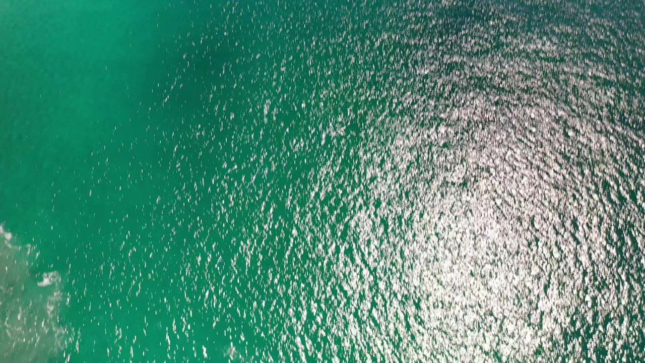 Green ocean water with sun sparkle and faint foam