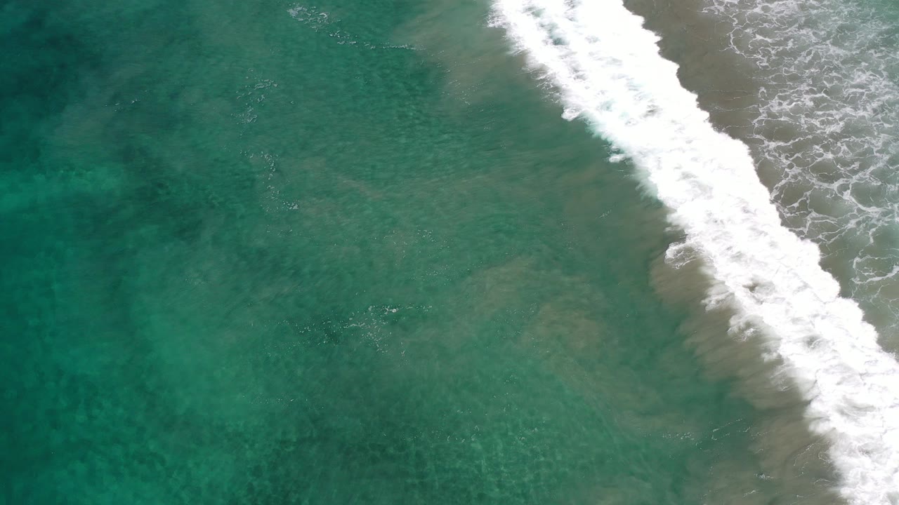 Overhead green-blue surf with a diagonal white breaking wave.