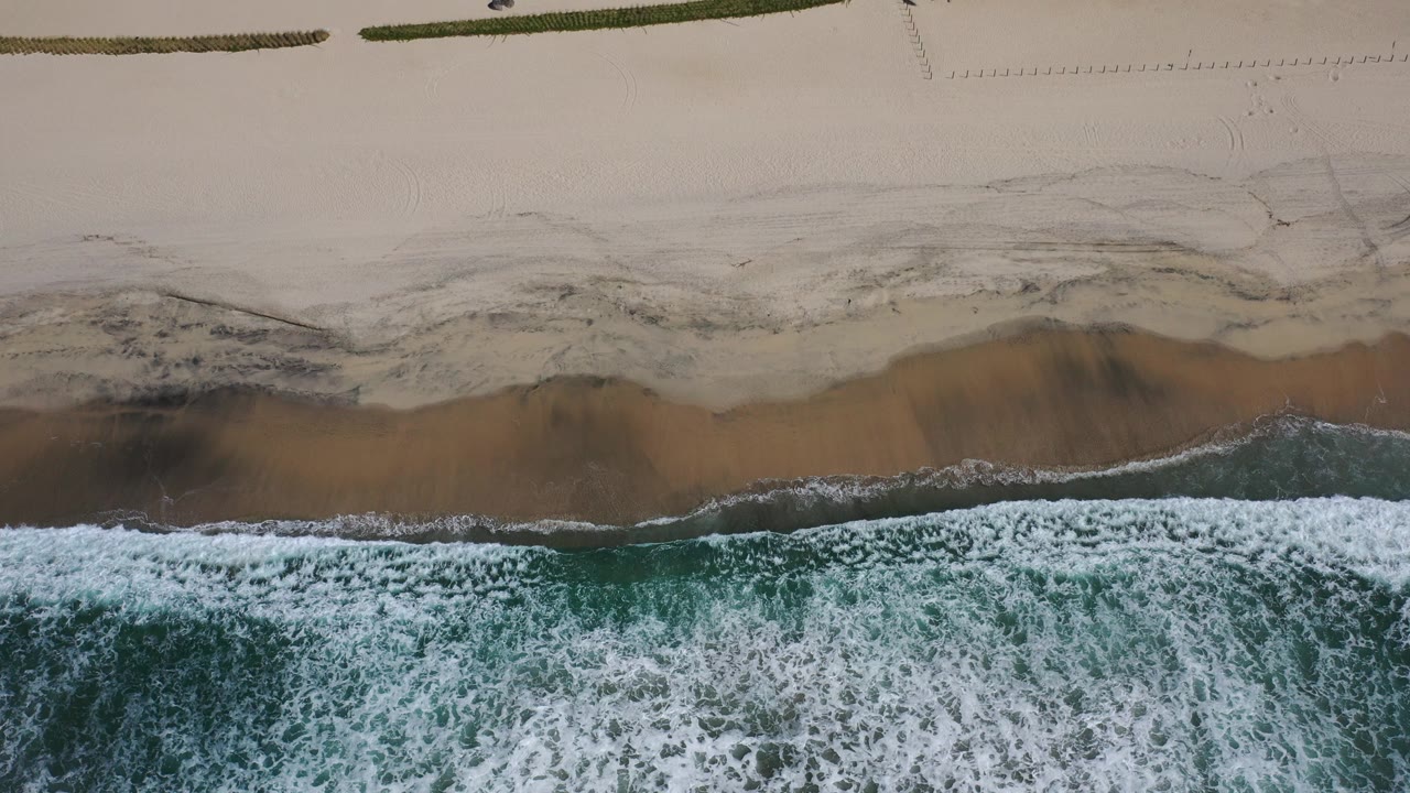Overhead surf breaking onto a sandy beach.