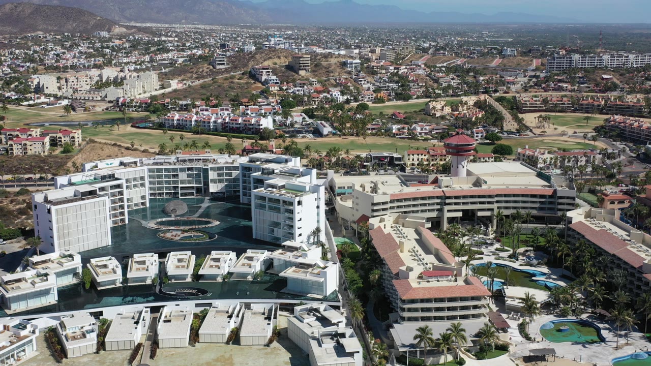 Aerial view of resort buildings, golf course, city blocks, and mountains