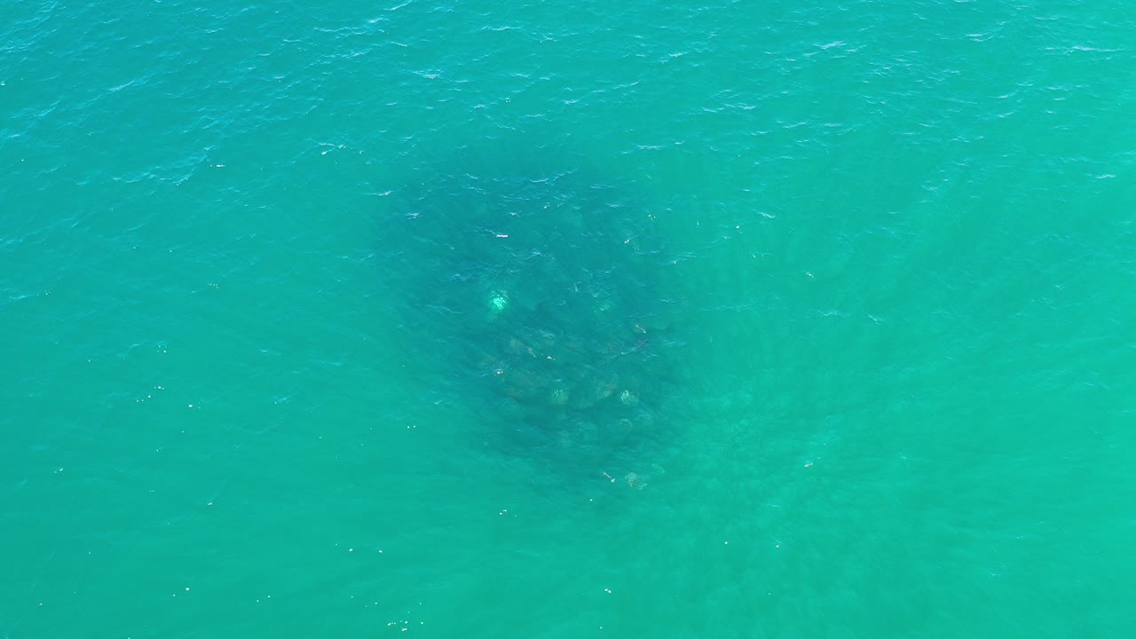 Overhead view of turquoise seawater in Los Cabos, Mexico, with a dark underwater patch left of center and no visible people.