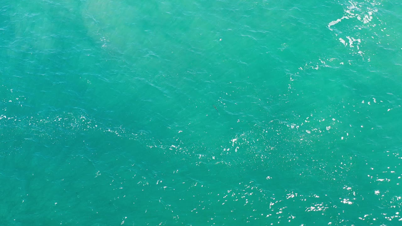 Turquoise sea surface with brighter patches near the top.