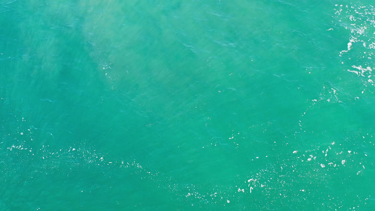 Turquoise water surface with fine ripples and pale underwater patches.