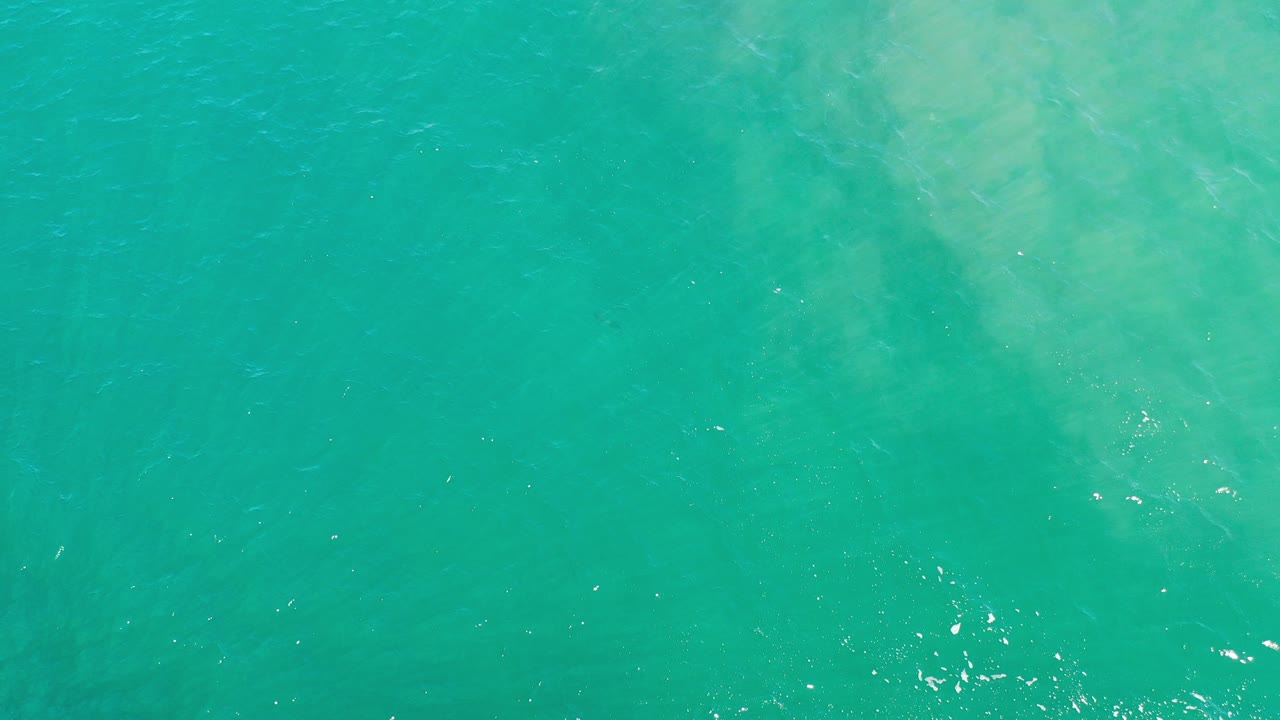 Top-down view of turquoise shallow seawater in Los Cabos, Mexico, with pale submerged patterns and no visible people.