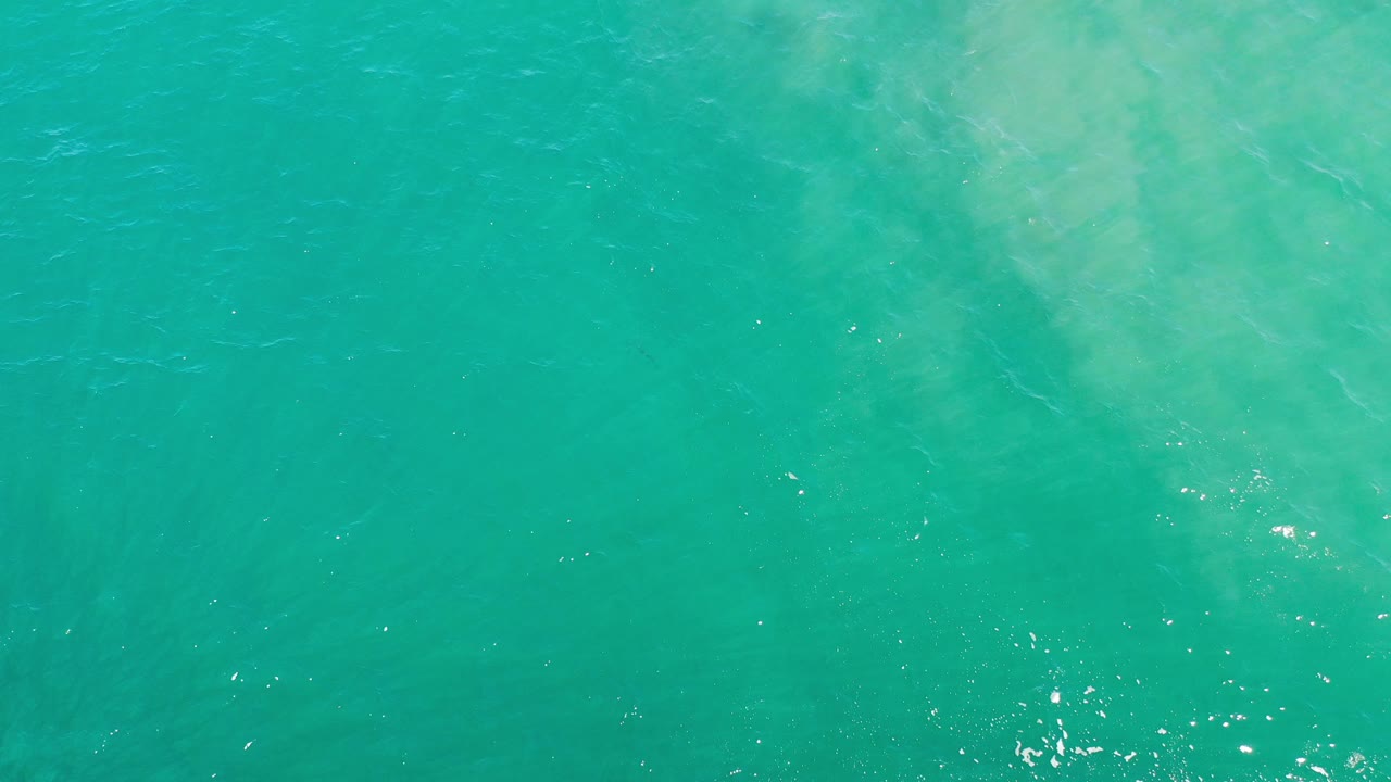 Turquoise sea surface with small bright glints.