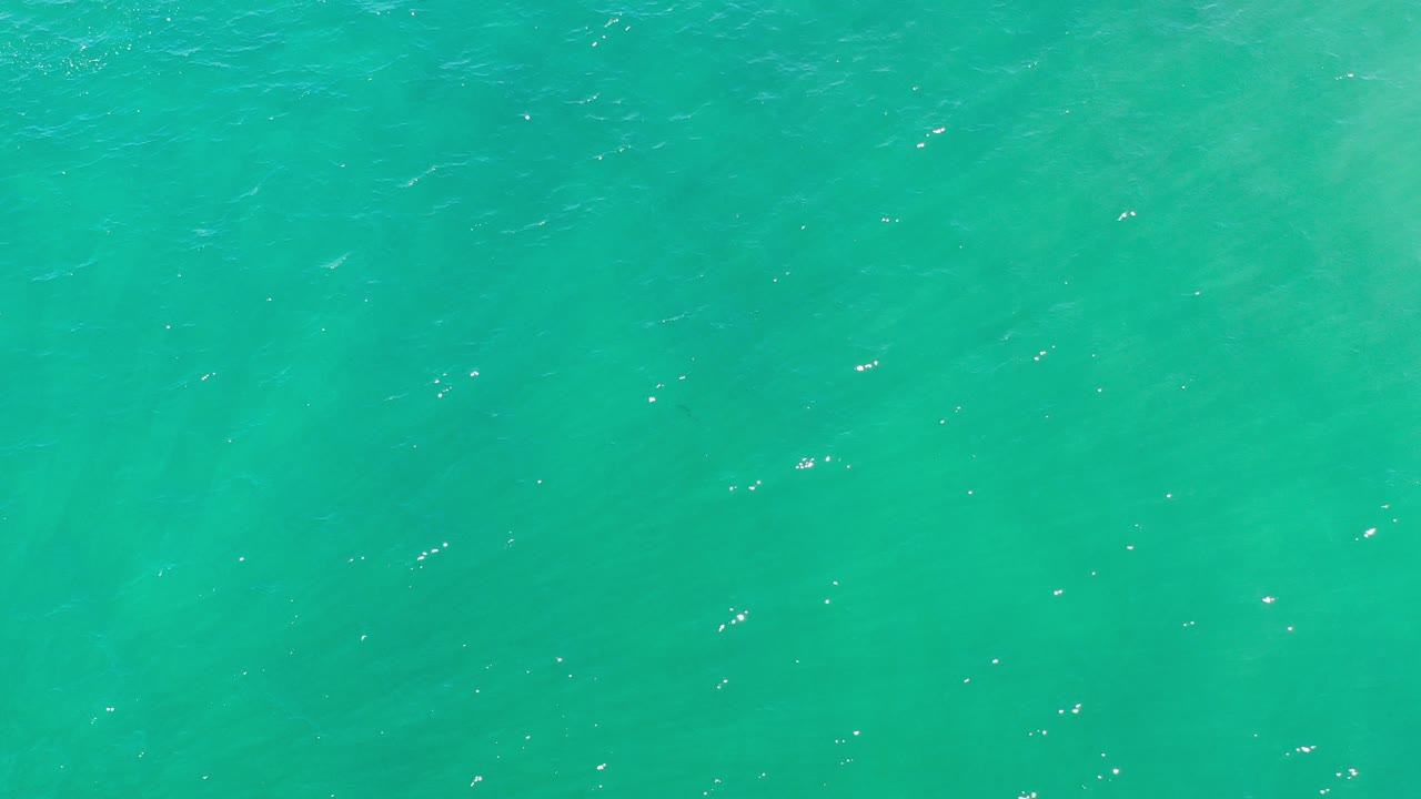 Turquoise sea water fills the opening frame in Los Cabos, Mexico, with scattered sun flecks and no visible people.