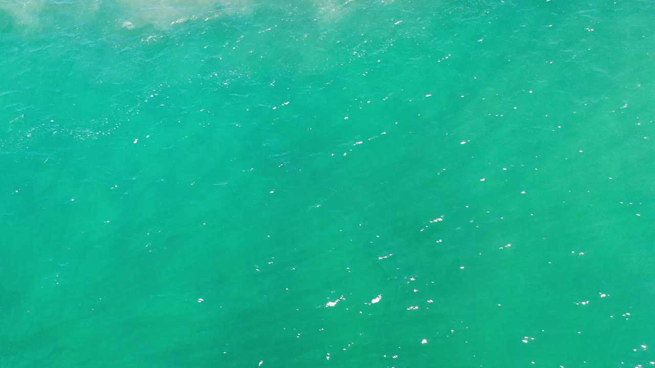 Aerial water frame from Los Cabos, Mexico, showing turquoise green sea with small white flecks across the surface and no visible people.