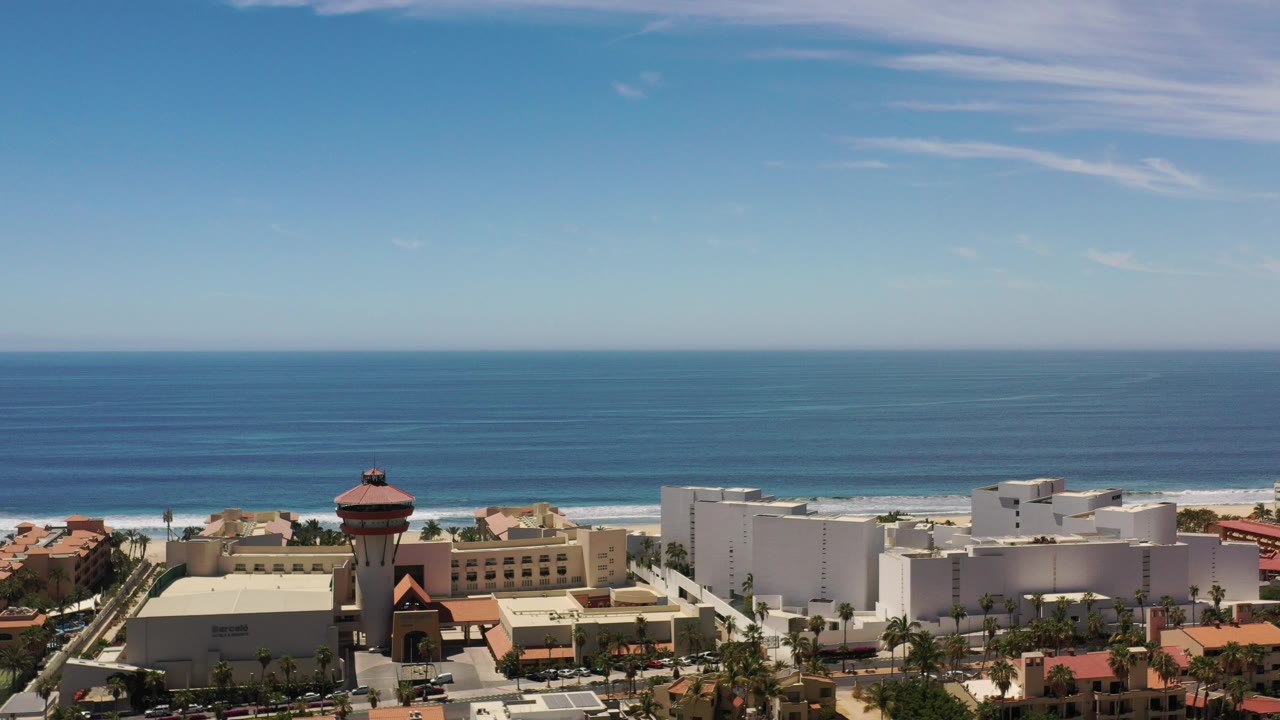 Aerial view of resort buildings, beach, ocean, and clear sky.