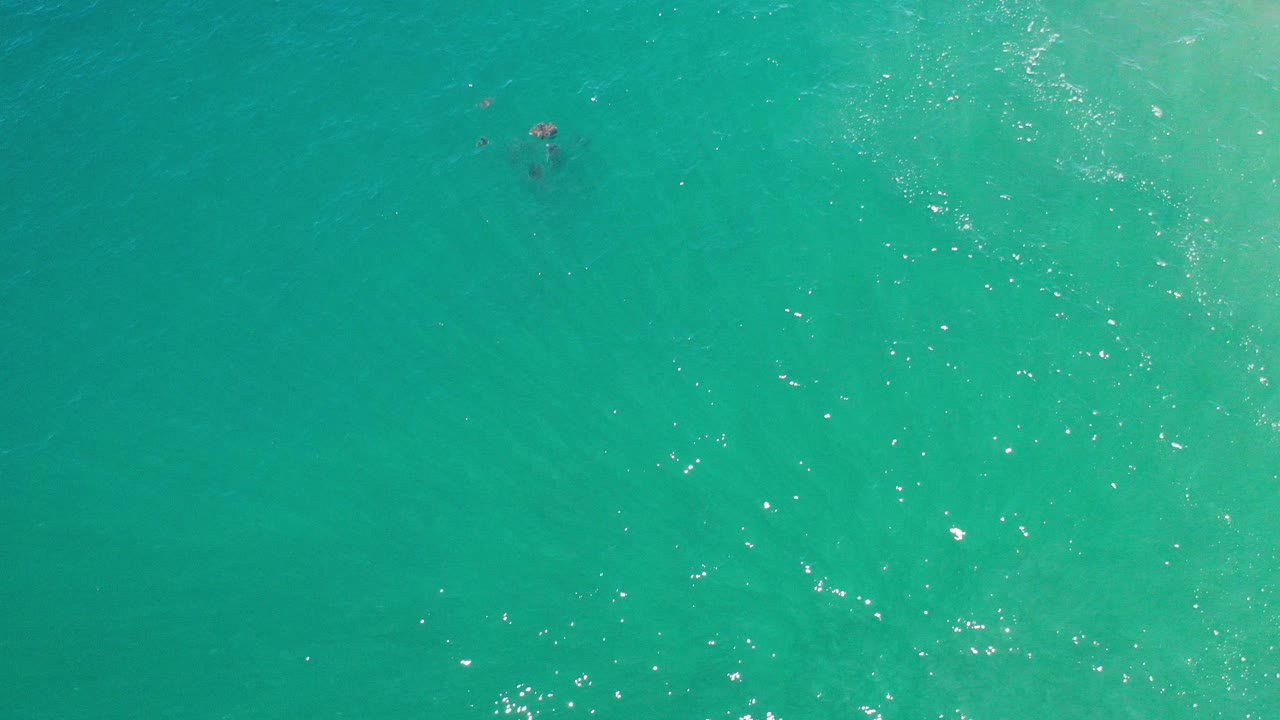 Overhead view of turquoise water in Los Cabos, Mexico, with scattered sparkle on small ripples and no visible people.