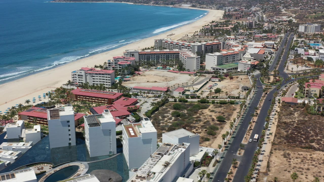 Aerial view of beachfront hotels, road, sand, and ocean.