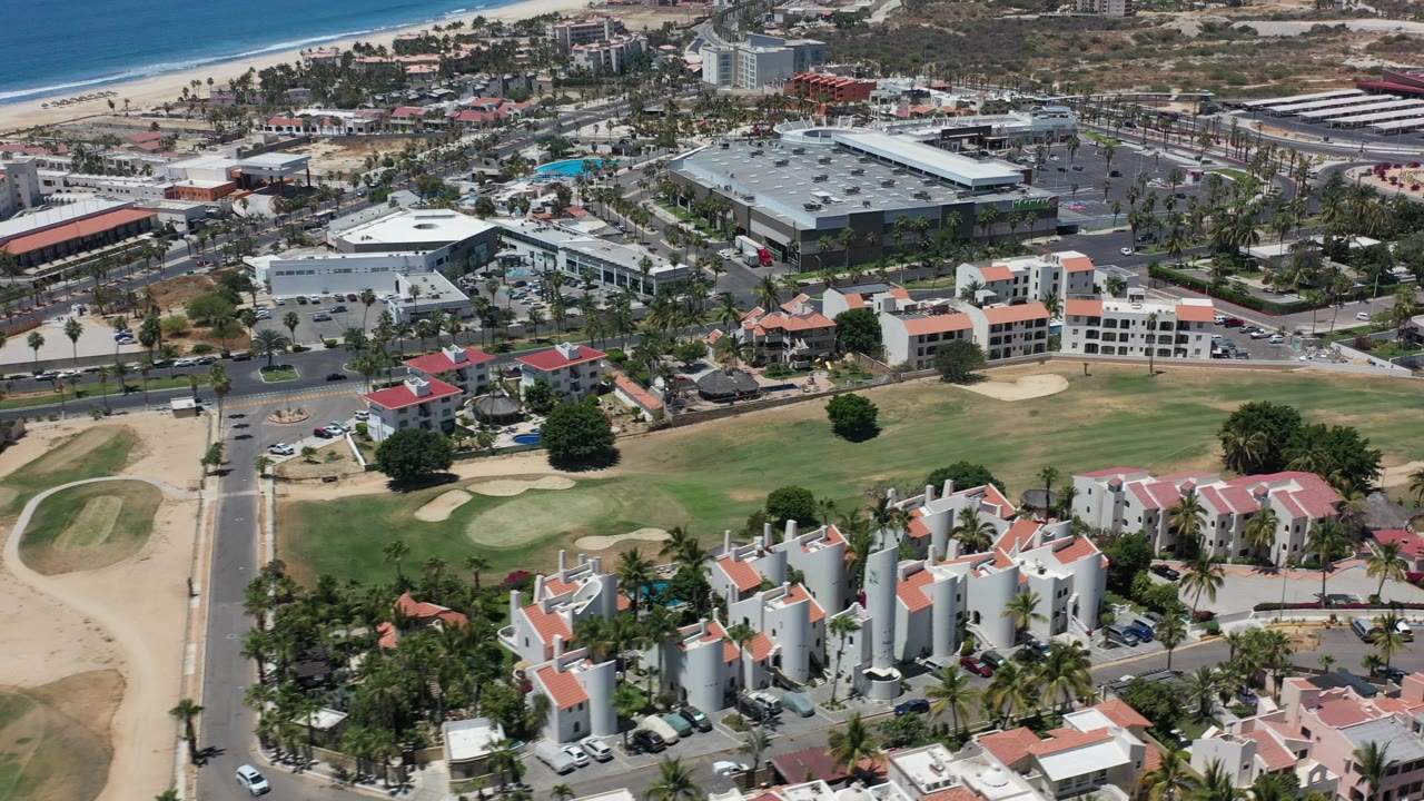 Aerial view of golf course, buildings, beach, and ocean.