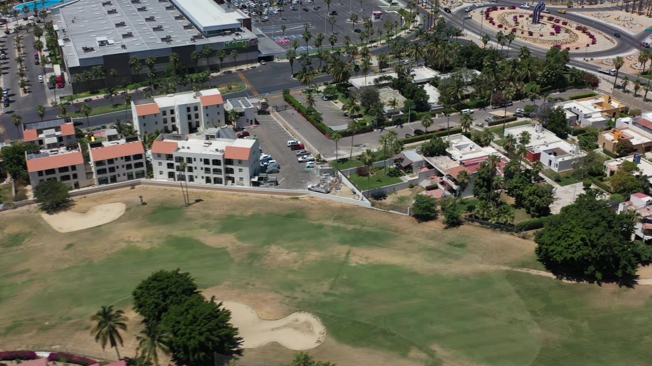 Oblique aerial view of fairway, building complex, residential blocks, and roads.
