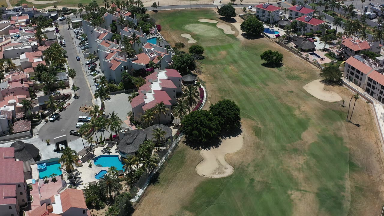 Condominium roofs, pools, and a golf course seen from above.