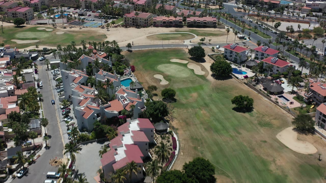 Aerial view of golf course, villas, roads, and oceanfront buildings