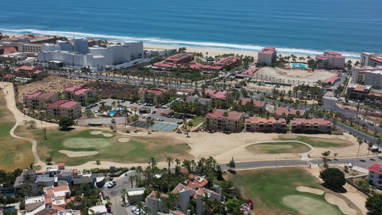 Aerial view of beachfront condominiums, golf course, and ocean surf.