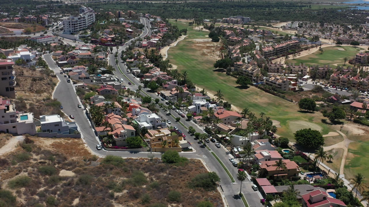 Aerial view of residential streets, homes, dry lots, and golf-course grass.