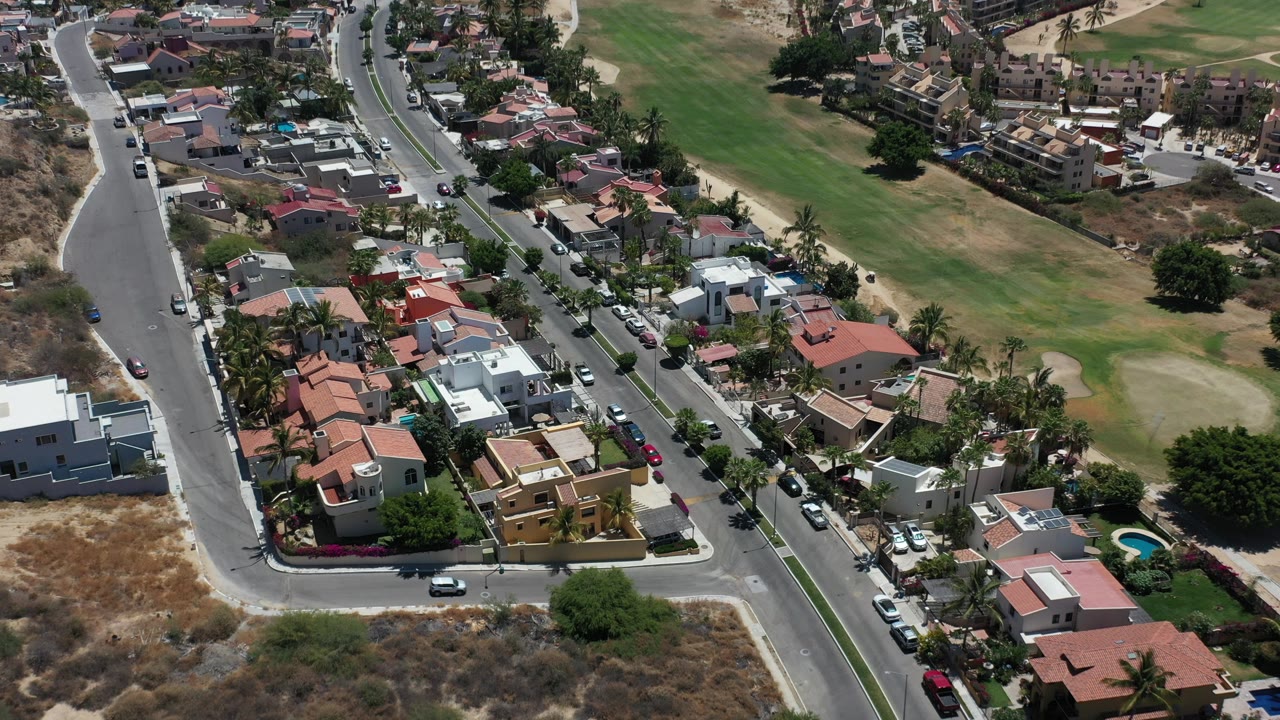 Aerial view of suburban homes beside a green open area and curving streets.