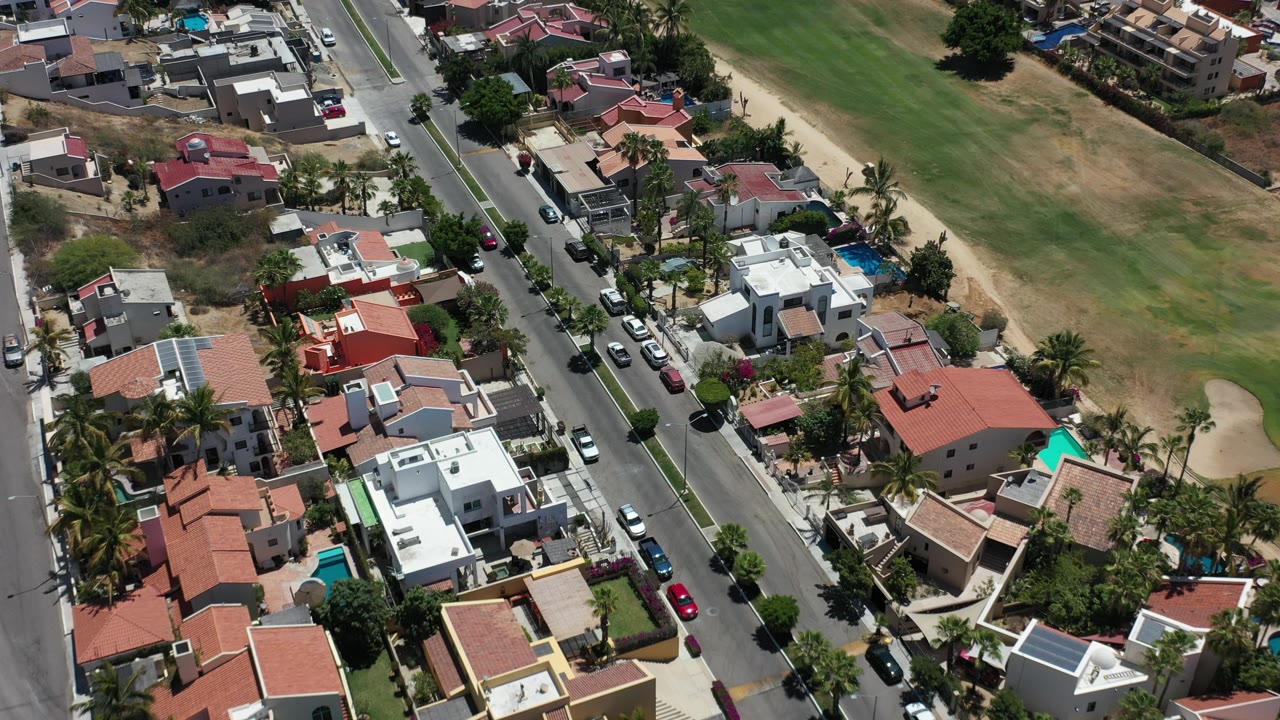 Aerial view of a residential street beside houses and open grassland.