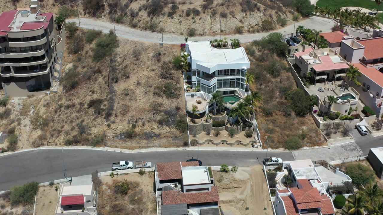 Aerial view of hillside homes beside a curving road.