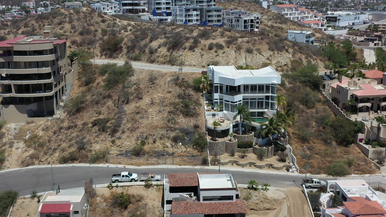 Dry hillside neighborhood with mansion and city beyond.