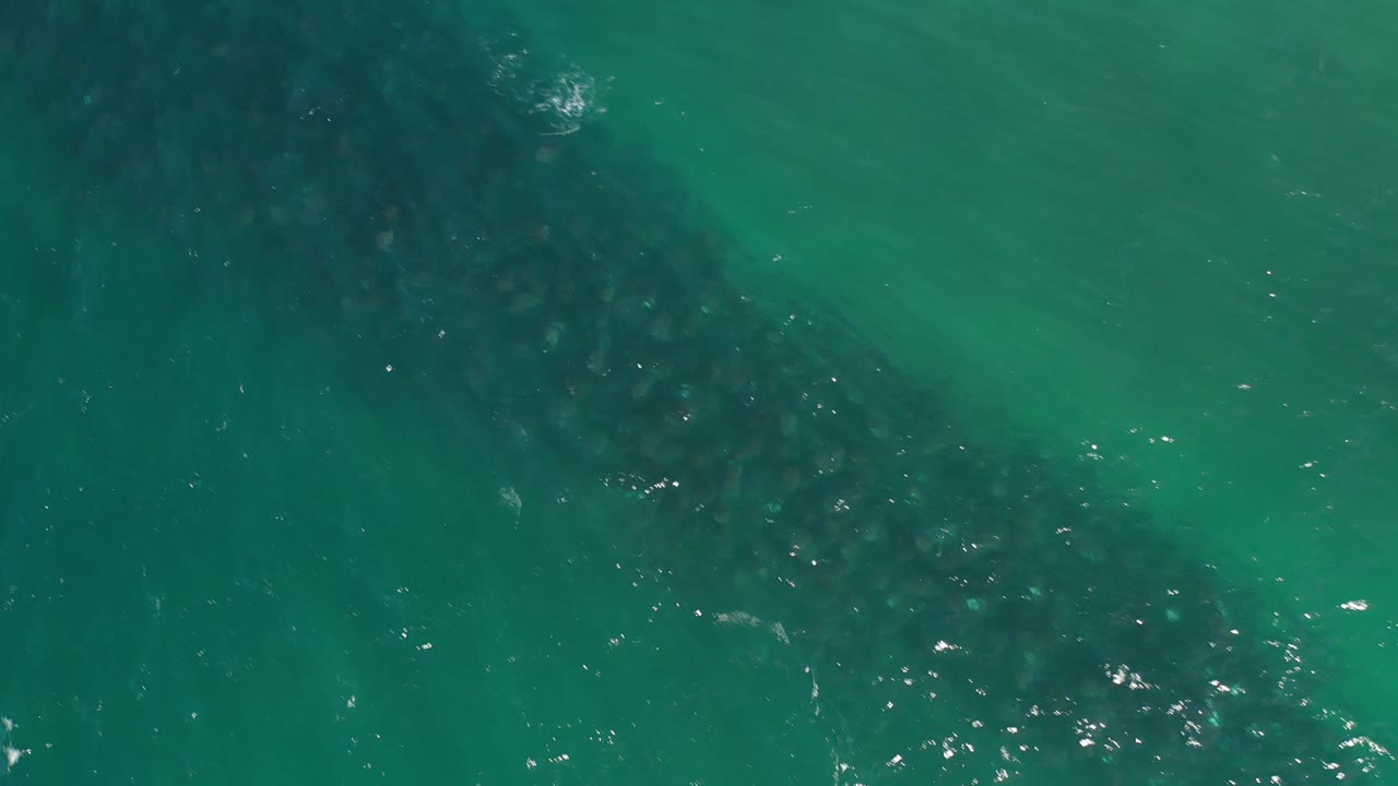 Turquoise water surface with darker underwater shapes and light sparkle.