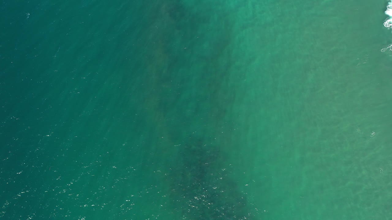 Overhead teal ocean water with faint current bands.