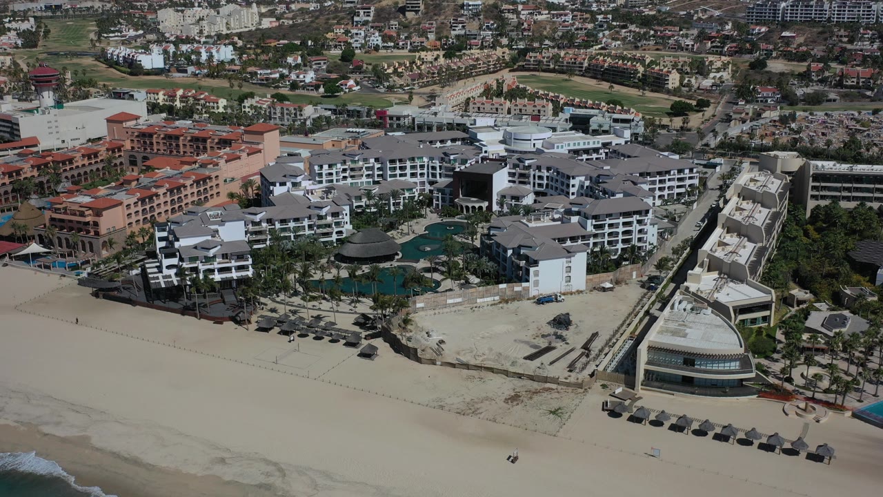 Aerial view of beachfront resort buildings beside a wide sandy beach.