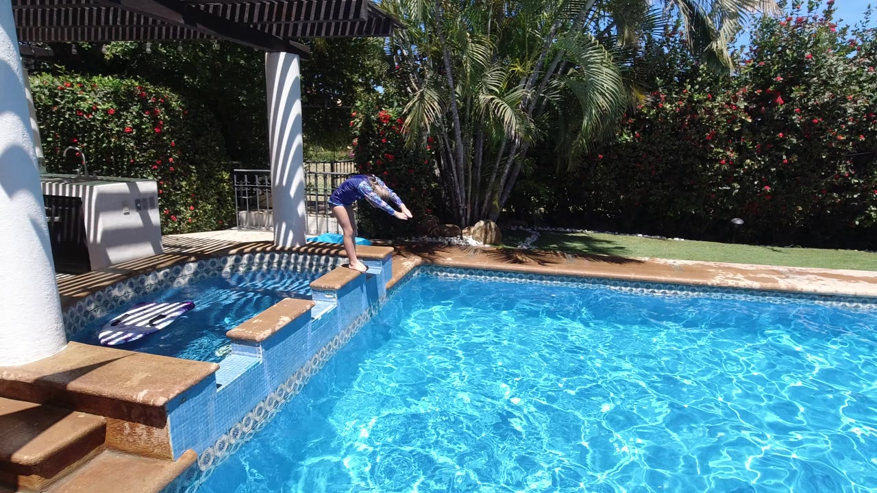Young girl leaning over a backyard pool before diving.