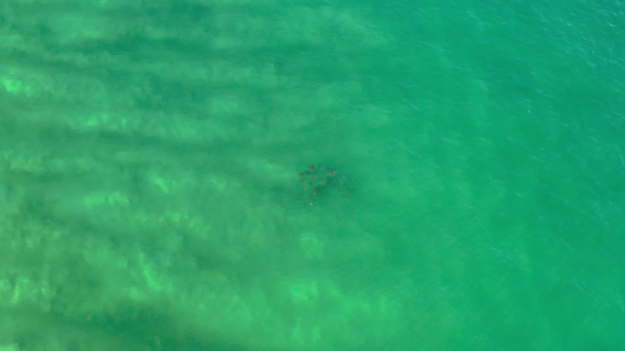 High-angle Los Cabos water frame with green-blue surface, hazy underwater shapes, and no visible people or boats.