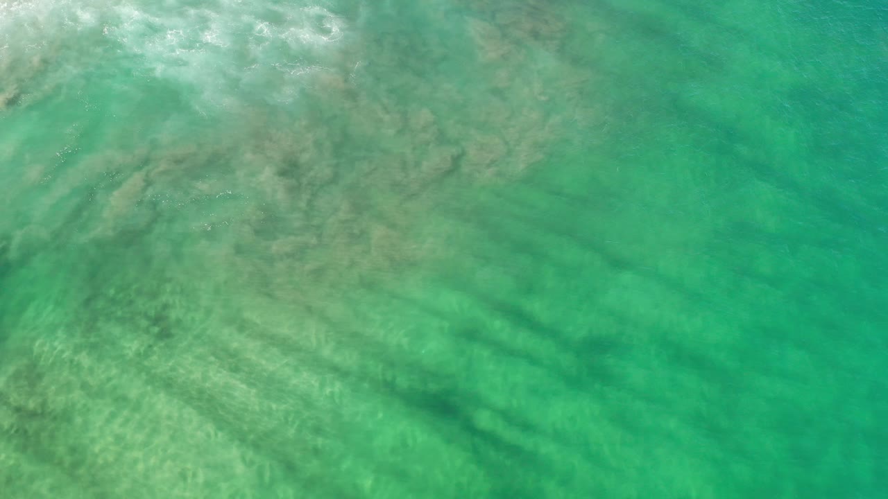 Green ocean water with cloudy patches and darker underwater bands.